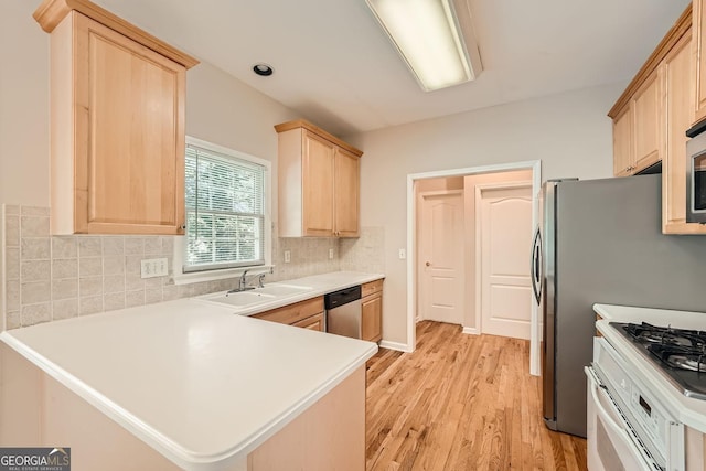 kitchen with sink, backsplash, stainless steel appliances, light hardwood / wood-style floors, and kitchen peninsula