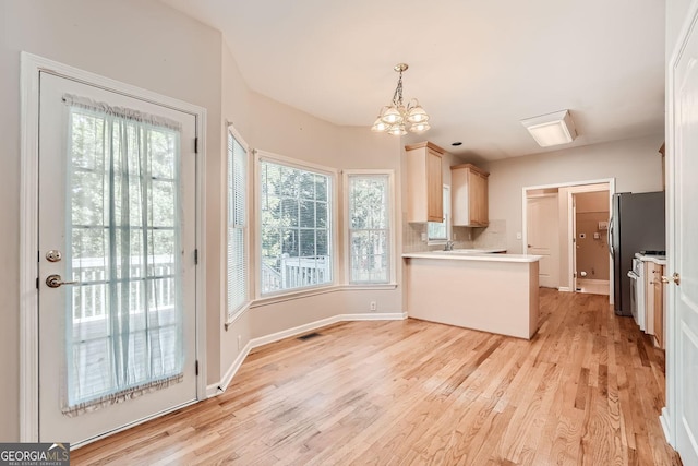 kitchen featuring light hardwood / wood-style flooring, stainless steel refrigerator, light brown cabinetry, decorative backsplash, and decorative light fixtures