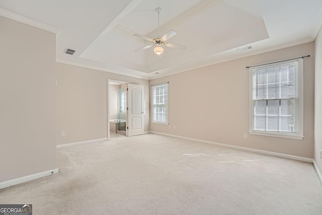 empty room with ornamental molding, light colored carpet, ceiling fan, and a tray ceiling