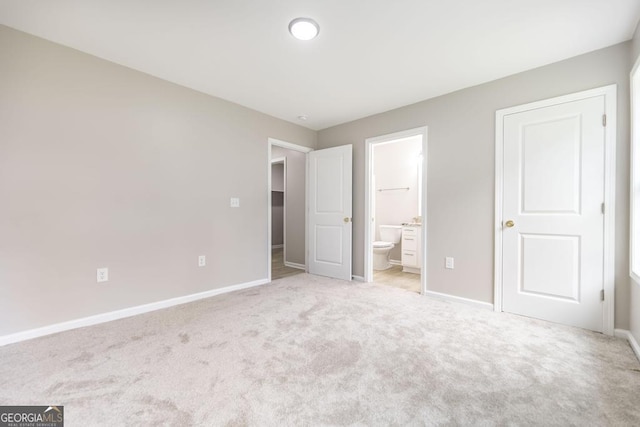 unfurnished bedroom with connected bathroom and light carpet