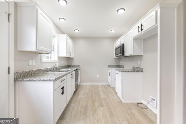 kitchen featuring light stone counters, sink, stainless steel appliances, and white cabinets