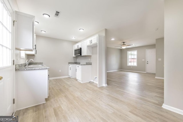 kitchen featuring white cabinetry, sink, light stone counters, ceiling fan, and light wood-type flooring