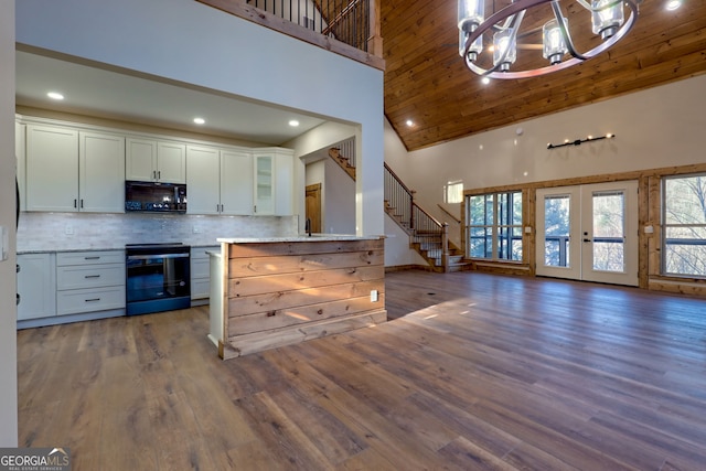 kitchen with white cabinetry, an inviting chandelier, a towering ceiling, range with electric cooktop, and dark hardwood / wood-style floors