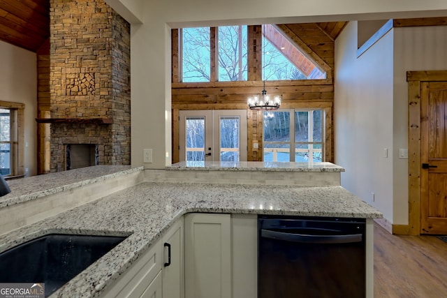 kitchen featuring a stone fireplace, white cabinetry, sink, light stone countertops, and a healthy amount of sunlight