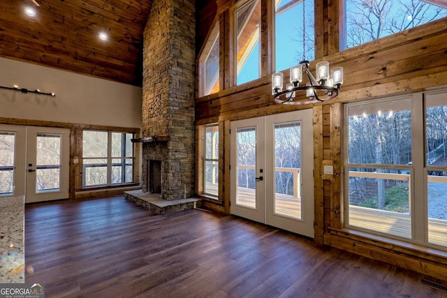 entryway featuring french doors, dark wood-type flooring, a chandelier, high vaulted ceiling, and a fireplace