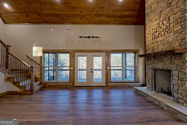 unfurnished living room with french doors, dark wood-type flooring, a fireplace, and a towering ceiling