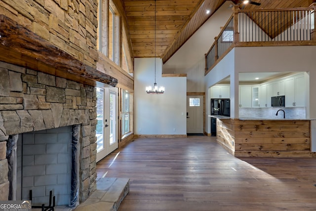 unfurnished living room with sink, wood ceiling, dark hardwood / wood-style floors, a notable chandelier, and a fireplace