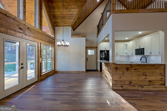 kitchen featuring light stone counters, decorative light fixtures, black appliances, dark hardwood / wood-style floors, and white cabinets