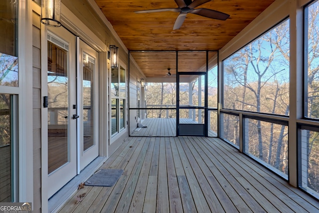 unfurnished sunroom featuring a healthy amount of sunlight, wood ceiling, and ceiling fan