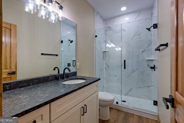 bathroom with walk in shower, vanity, toilet, and wood-type flooring