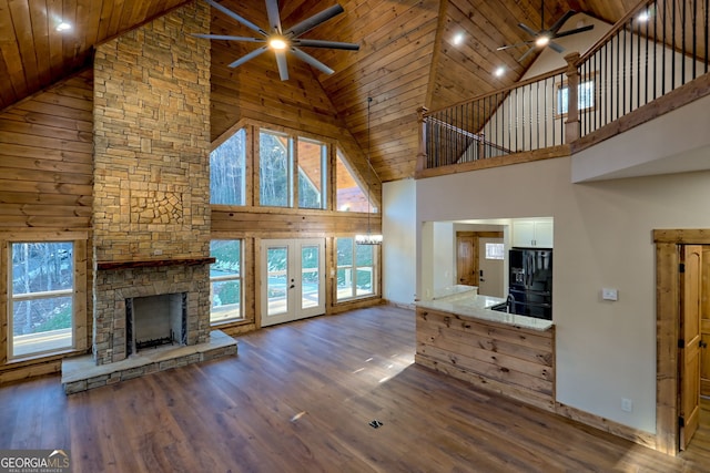 unfurnished living room featuring dark wood-type flooring, a fireplace, ceiling fan, and french doors