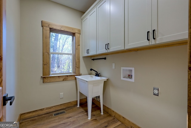 laundry room with cabinets, light hardwood / wood-style floors, hookup for a washing machine, and electric dryer hookup