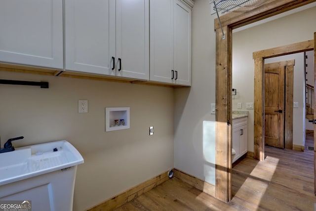 laundry room featuring washer hookup, light hardwood / wood-style floors, and cabinets