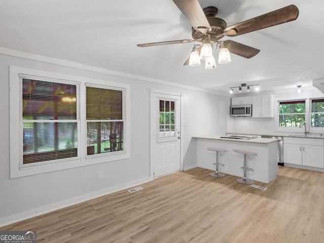 kitchen featuring a breakfast bar area, white cabinetry, light wood-type flooring, appliances with stainless steel finishes, and kitchen peninsula