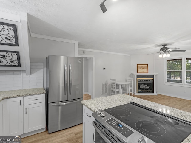 kitchen with light hardwood / wood-style flooring, ceiling fan, white cabinetry, stainless steel appliances, and tasteful backsplash