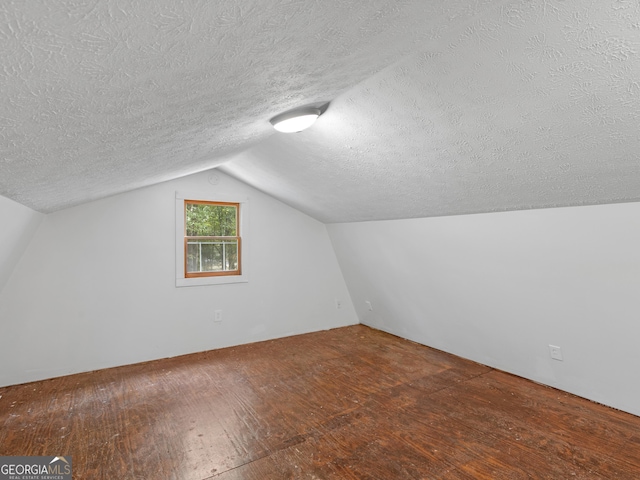 additional living space featuring vaulted ceiling, hardwood / wood-style floors, and a textured ceiling