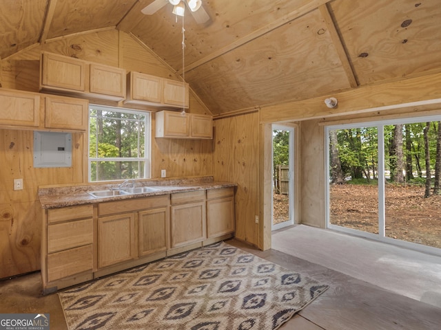 kitchen featuring vaulted ceiling, light brown cabinetry, sink, and wood walls