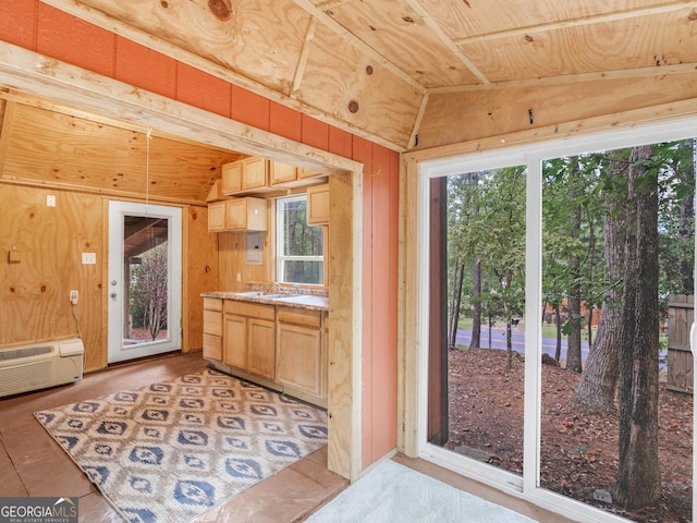 interior space with vaulted ceiling, light brown cabinets, and wooden walls