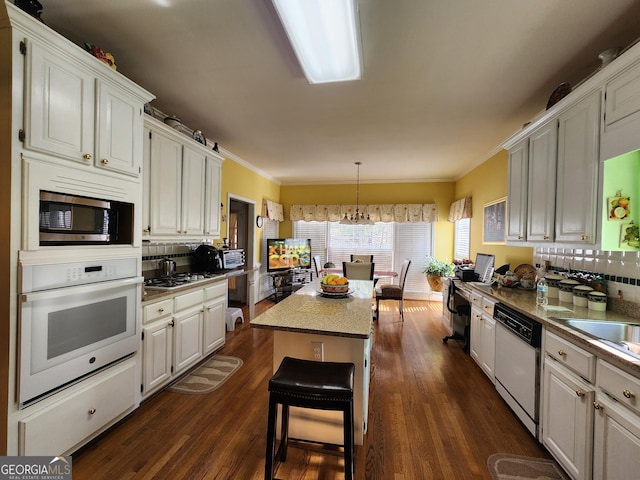 kitchen with dark wood-type flooring, tasteful backsplash, white cabinetry, a center island, and appliances with stainless steel finishes