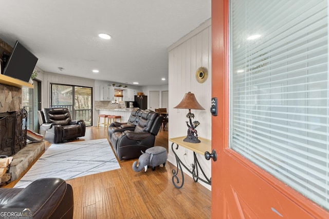 living room with a stone fireplace and light hardwood / wood-style floors