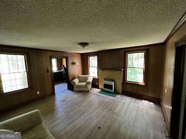 unfurnished living room featuring crown molding, a textured ceiling, heating unit, and light wood-type flooring