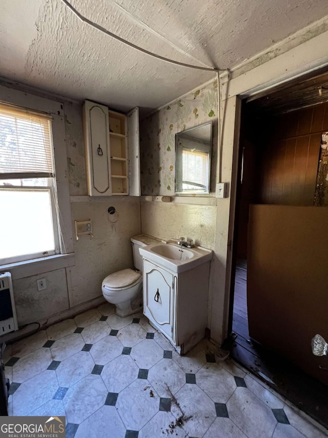 bathroom featuring vanity, heating unit, a textured ceiling, and toilet