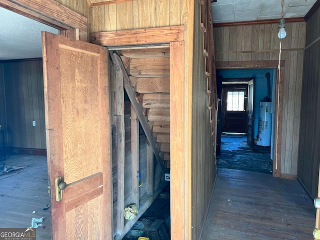 corridor featuring gas water heater, wood-type flooring, and wood walls