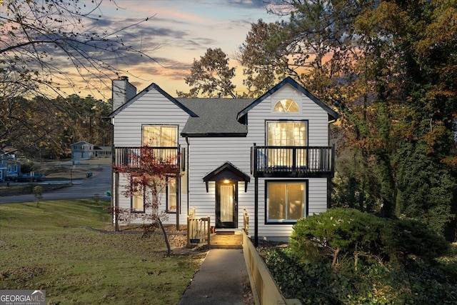 view of front of property featuring a lawn and a balcony