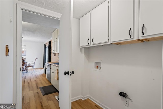 laundry area with washer hookup, cabinets, a textured ceiling, and light wood-type flooring