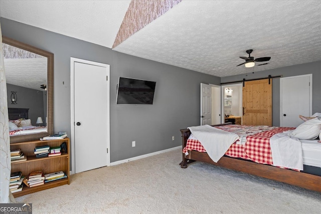 bedroom with ceiling fan, a barn door, carpet, and a textured ceiling