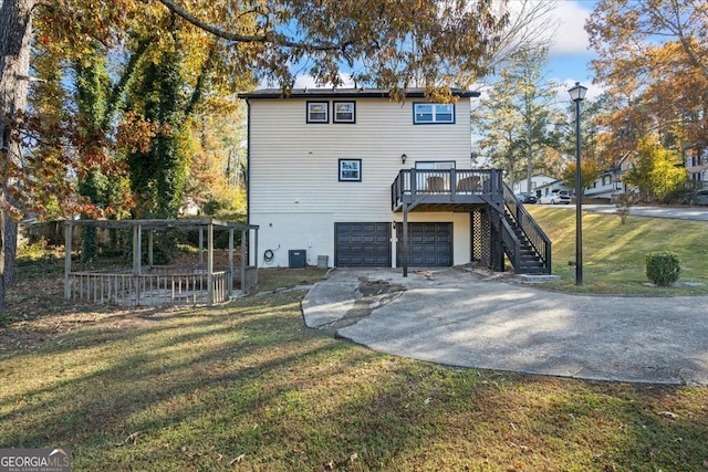 back of property featuring a wooden deck, a garage, a yard, and central AC unit