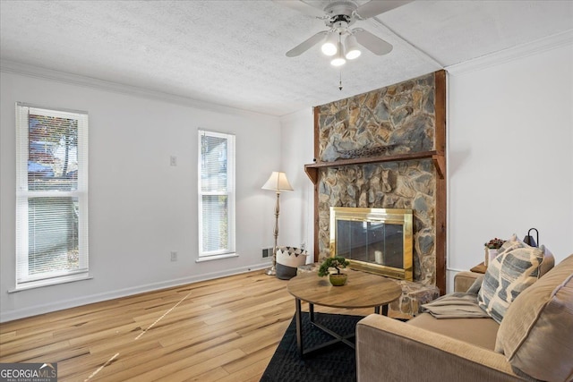 living room featuring crown molding, hardwood / wood-style flooring, a fireplace, and a textured ceiling