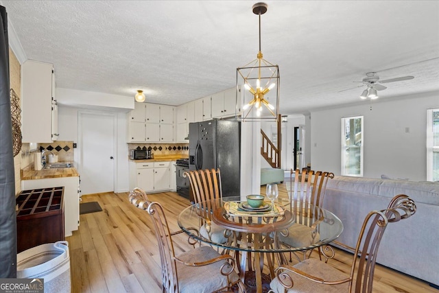 dining room with sink, ceiling fan with notable chandelier, light hardwood / wood-style floors, and a textured ceiling