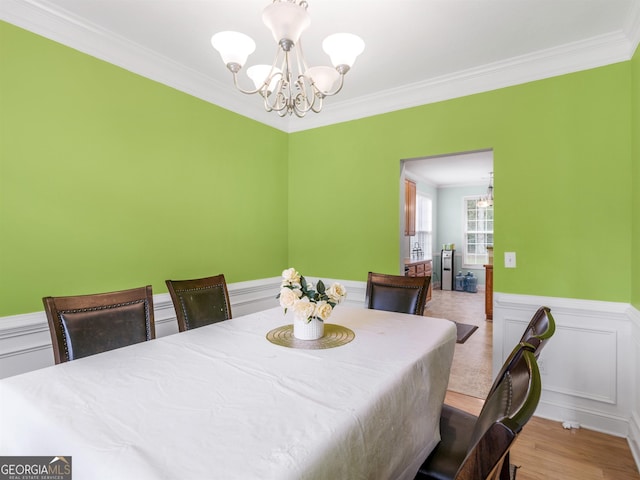 dining area with crown molding, a chandelier, and light hardwood / wood-style floors