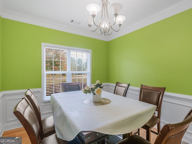 dining space with ornamental molding, a notable chandelier, and light wood-type flooring