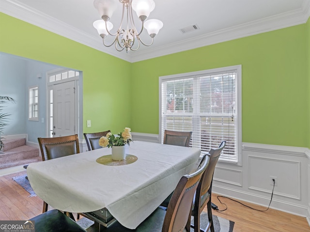 dining area with an inviting chandelier, crown molding, and light hardwood / wood-style flooring