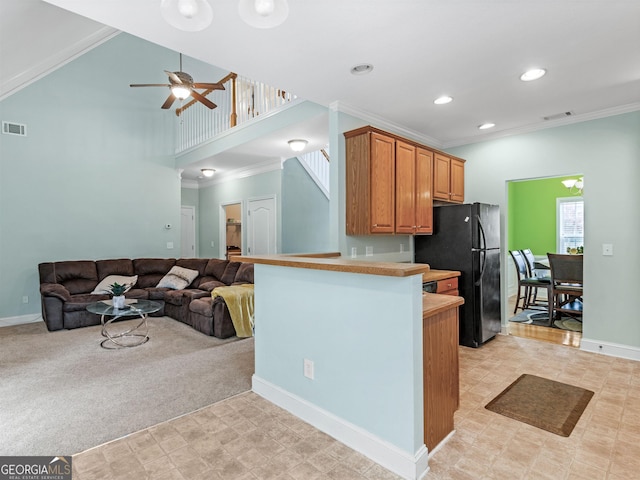 kitchen with black refrigerator, ceiling fan, ornamental molding, kitchen peninsula, and light colored carpet