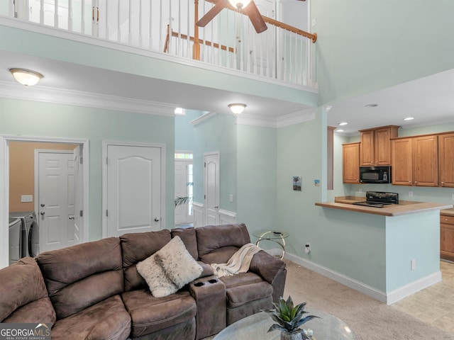 carpeted living room featuring crown molding, washing machine and clothes dryer, and a high ceiling