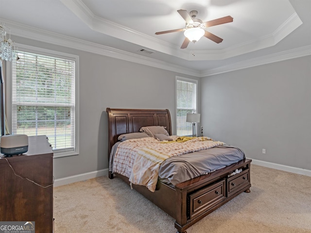 bedroom with ornamental molding, light carpet, ceiling fan, and a tray ceiling