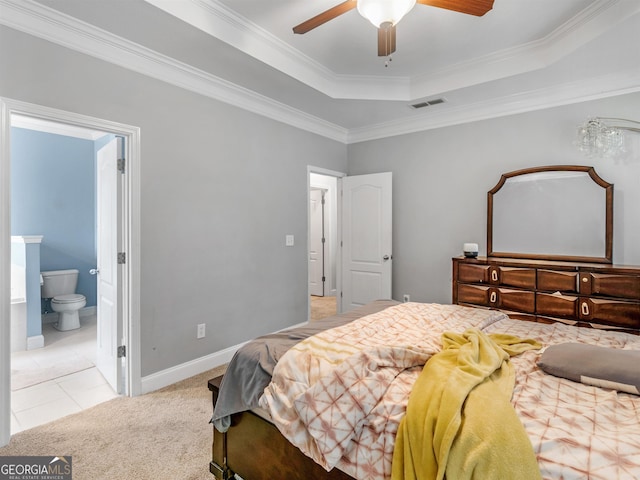 bedroom featuring crown molding, ensuite bath, ceiling fan, a tray ceiling, and light colored carpet