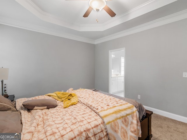 bedroom featuring crown molding, ensuite bath, ceiling fan, a tray ceiling, and light colored carpet