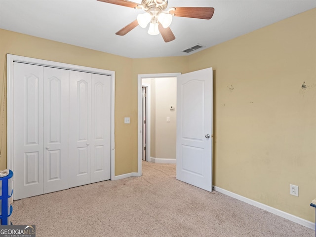 unfurnished bedroom featuring ceiling fan, light colored carpet, and a closet