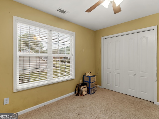 unfurnished bedroom with ceiling fan, light colored carpet, and a closet