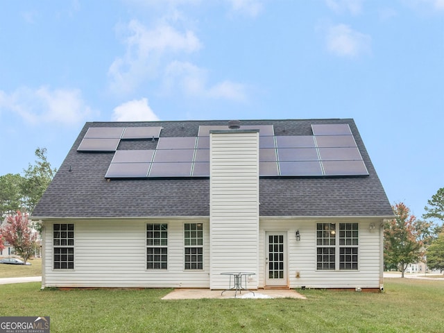 rear view of house with a yard, a patio area, and solar panels