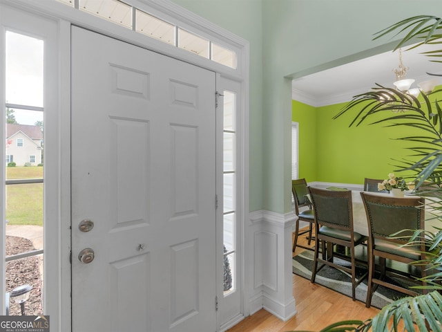 entrance foyer with crown molding, a wealth of natural light, and light wood-type flooring