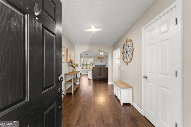 hallway with a textured ceiling and dark hardwood / wood-style flooring