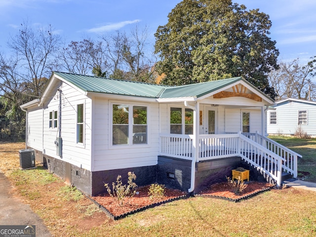 view of front of property with covered porch, a front yard, and central air condition unit