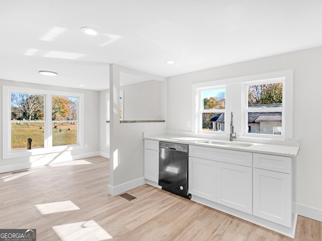 kitchen with sink, dishwasher, white cabinetry, light stone countertops, and light wood-type flooring