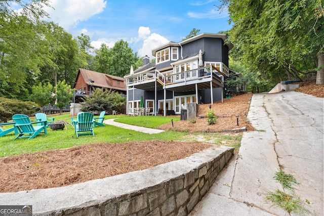 back of house featuring a wooden deck, a yard, and a fire pit