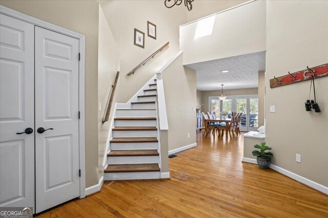 stairs featuring hardwood / wood-style flooring and a notable chandelier